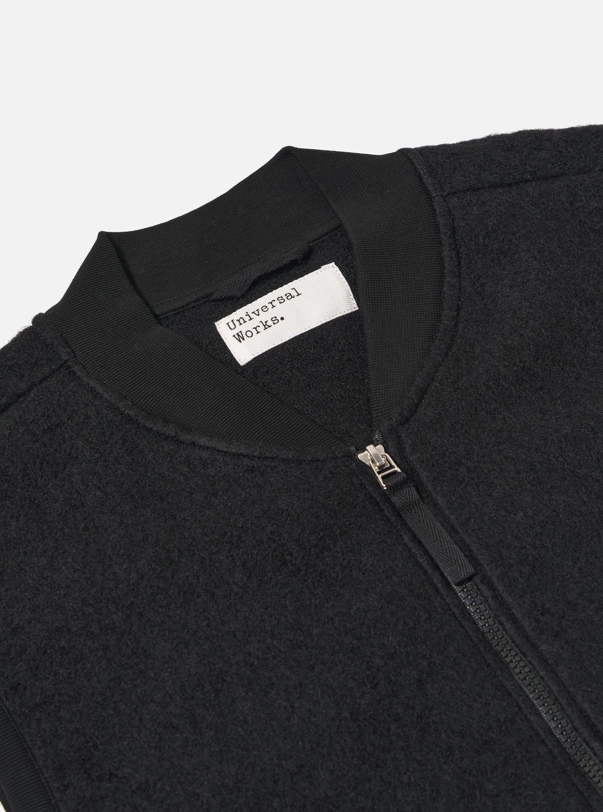 Close-up of the Black Wool Fleece Zip Waistcoat, showcasing the texture and zipper detail. Shot against a plain background.