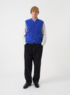 A male model wears the Universal Works Blue Wool Fleece Zip Waistcoat zipped up over a collared shirt against a plain studio background. The shot highlights the regular fit silhouette, front zip closure, and patch pockets.