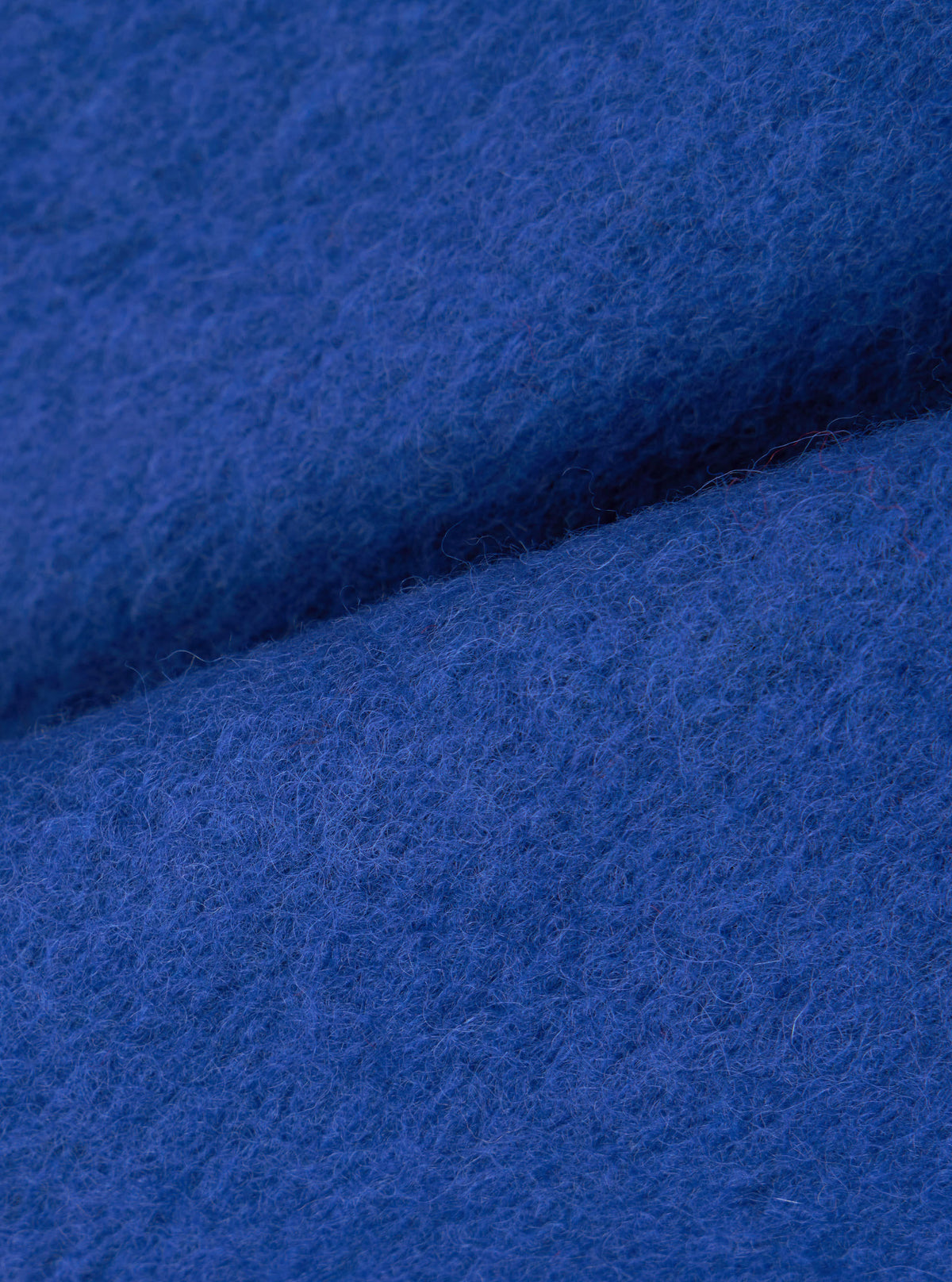 Close-up detail shot of the blue wool fleece material on the Universal Works Blue Wool Fleece Zip Waistcoat against a white background, highlighting the rich blue color, soft nubby texture, and cozy wool-blend fabric structure.