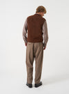 Angled view of a model wearing the Cacao Wool Fleece Zip Waistcoat in a plain studio setting. The shot demonstrates the garment fit from the side, highlighting the armhole cut and cacao brown wool fleece texture.