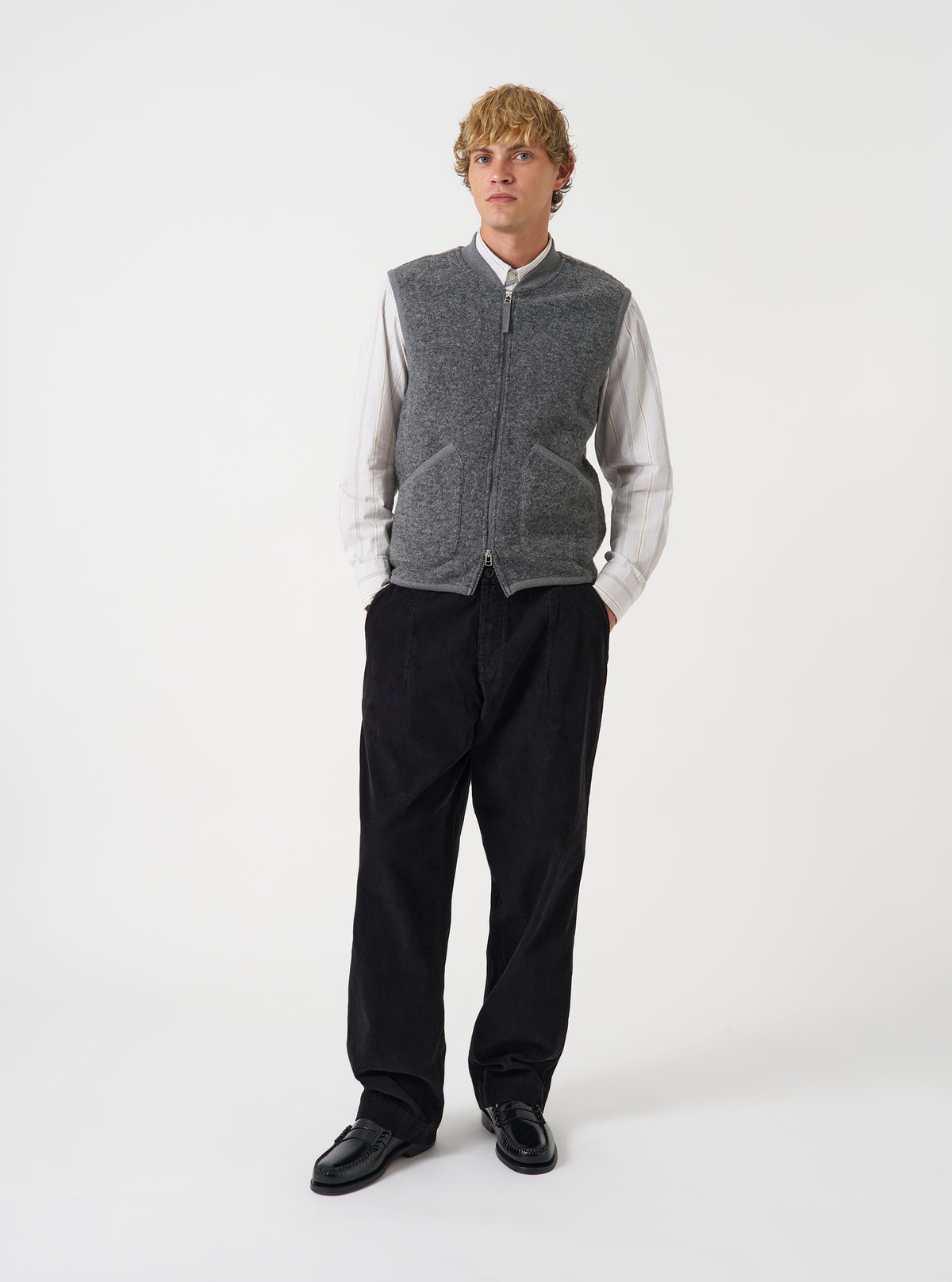 Front view of a model wearing the Grey Marl Wool Fleece Zip Waistcoat layered over a top in a studio setting with a light backdrop. The model stands facing forward, showing how the grey marl fleece waistcoat fits.