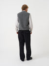 Angled view of a model wearing the Grey Marl Wool Fleece Zip Waistcoat in a plain studio setting. The shot demonstrates the garment fit from the side, highlighting the armhole cut and grey marl wool fleece texture.