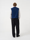 Angled view of a model wearing the Indigo Wool Fleece Zip Waistcoat in a plain studio setting. The shot demonstrates the garment fit from the side, highlighting the armhole cut and indigo wool fleece texture.
