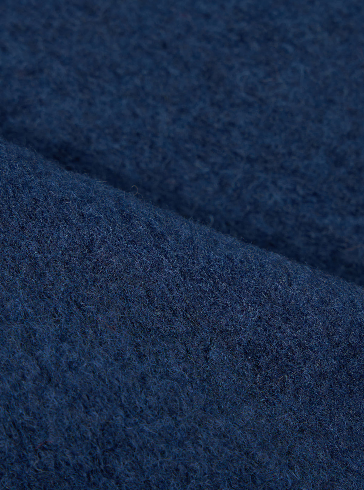 Extreme close-up fabric swatch image showcasing the texture of the Indigo Wool Fleece Zip Waistcoat. The detailed shot highlights the rich indigo blue tone, soft fibers, and cozy tactile feel of the wool fleece material.