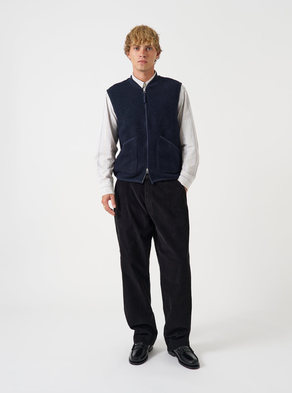 Front view of a model wearing the Navy Wool Fleece Zip Waistcoat layered over a top in a studio setting with a light backdrop. The model stands facing forward, showing how the navy fleece waistcoat fits.
