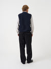 Angled view of a model wearing the Navy Wool Fleece Zip Waistcoat in a plain studio setting. The shot demonstrates the garment fit from the side, highlighting the armhole cut and navy wool fleece texture.