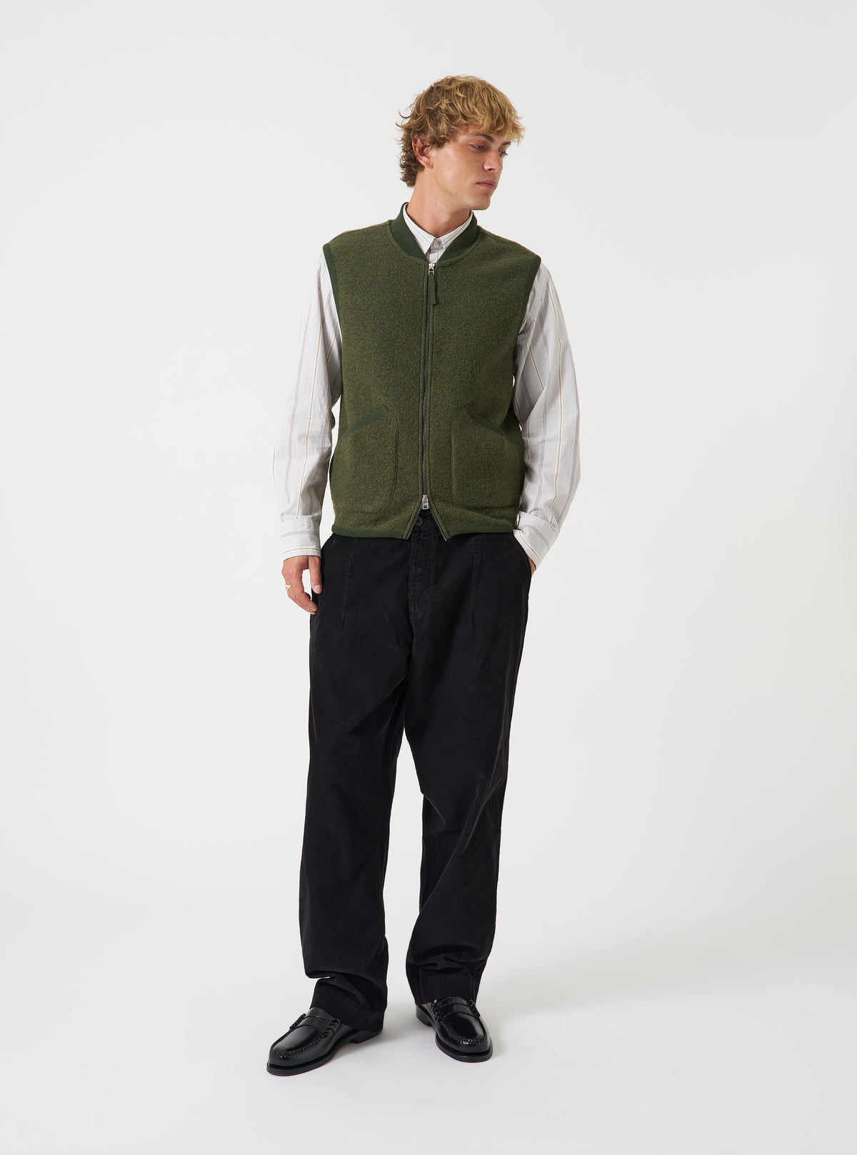 Front view of a model wearing the Olive Wool Fleece Zip Waistcoat in a studio setting. The model stands facing forward, showing how the green olive fleece waistcoat fits when layered over a garment.