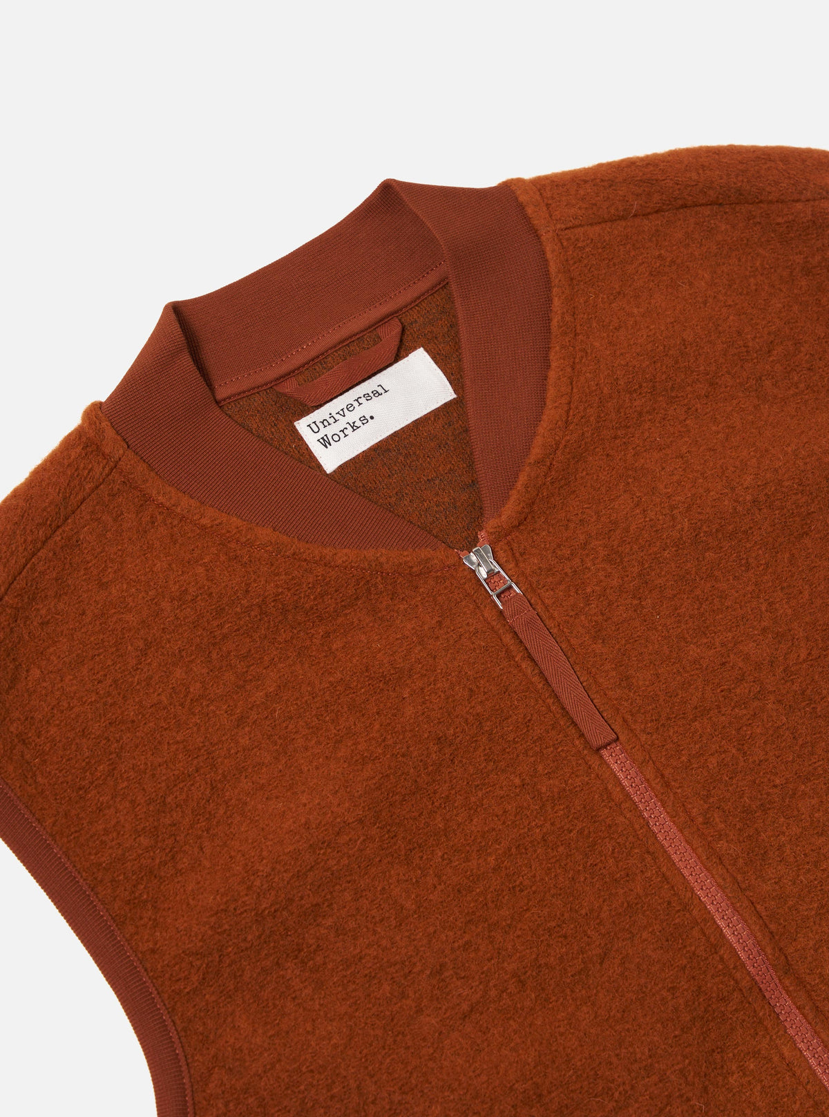 Close-up of the Rust Wool Fleece Zip Waistcoat on a white background. The rust-colored wool fleece vest features a zip closure and a ribbed collar.