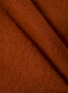 Close-up of the rust-colored wool fleece fabric of the Zip Waistcoat. The soft material is draped to show texture. 