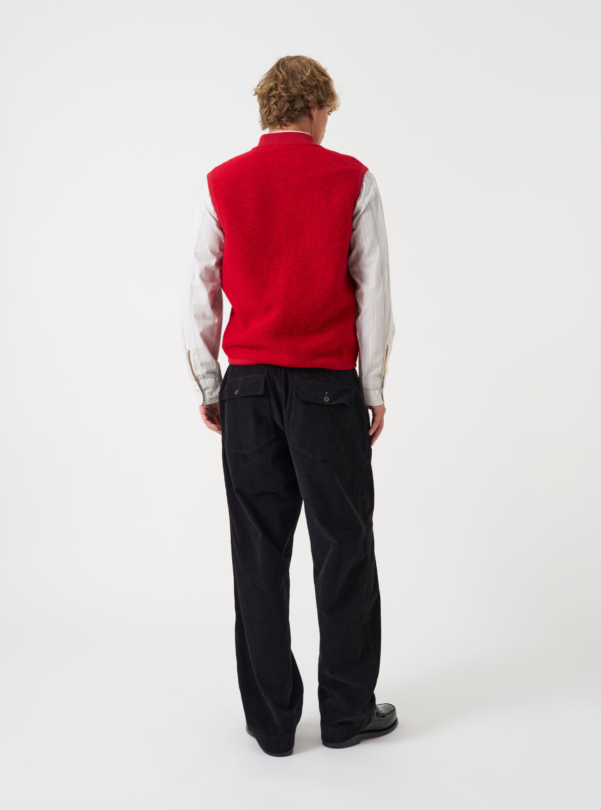 Side angled view of a model wearing the Scarlet Wool Fleece Zip Waistcoat in a plain studio. The image highlights the fit, armhole design, and soft red wool fleece texture from an alternate perspective.