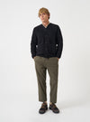 Front view of a model wearing the Black Wool Fleece Cardigan in a studio setting with a plain light backdrop. The model stands facing forward, showing the five-button front closure and chest patch pocket.