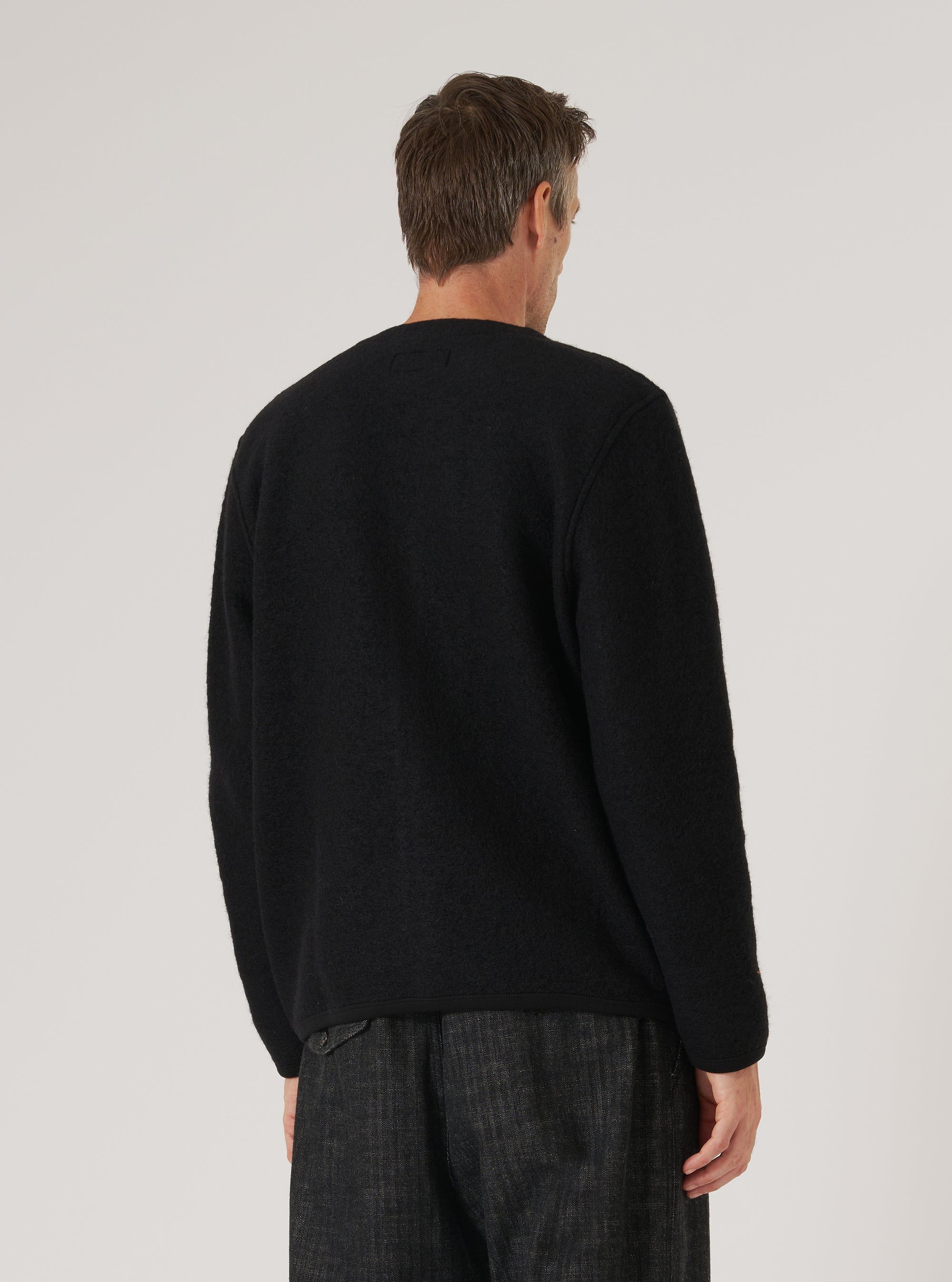 Back view of a man wearing a Black Wool Fleece Cardigan. The image is shot in a studio with a plain background. The cardigan has a relaxed fit.
