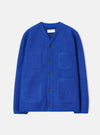 Blue wool fleece cardigan laid flat on a light grey studio backdrop. V-neckline with a branded woven label at the collar. Five dark horn buttons down the centre front. Two chest patch pockets and two larger patch pockets at the hem. Brushed wool fleece texture throughout. Straight hem and long sleeves with no cuffs.
