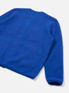 Back view of a blue wool fleece cardigan, laid flat on a light grey studio surface. The shot is cropped to show the back panel, one full sleeve, and a ribbed cuff. The fabric has a brushed, boiled-wool texture throughout. A small woven label is visible at the centre back neckline.