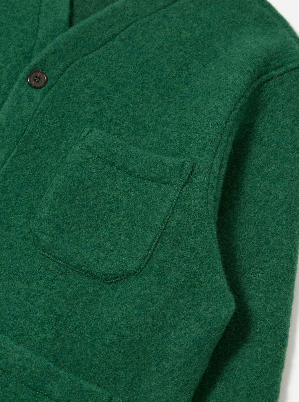 Close-up of a green wool fleece cardigan with a pocket, showcasing the material and texture. The Green Wool Fleece Cardigan is on a white surface.