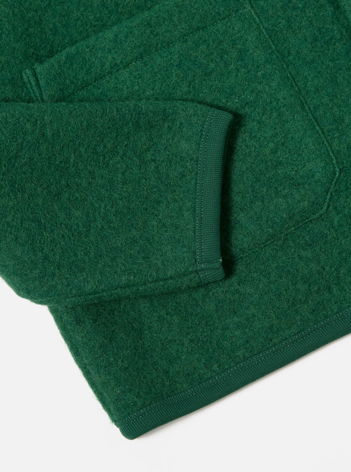 Close-up of the Green Wool Fleece Cardigan sleeve and pocket, showcasing the material's texture and ribbed trim on a white background.