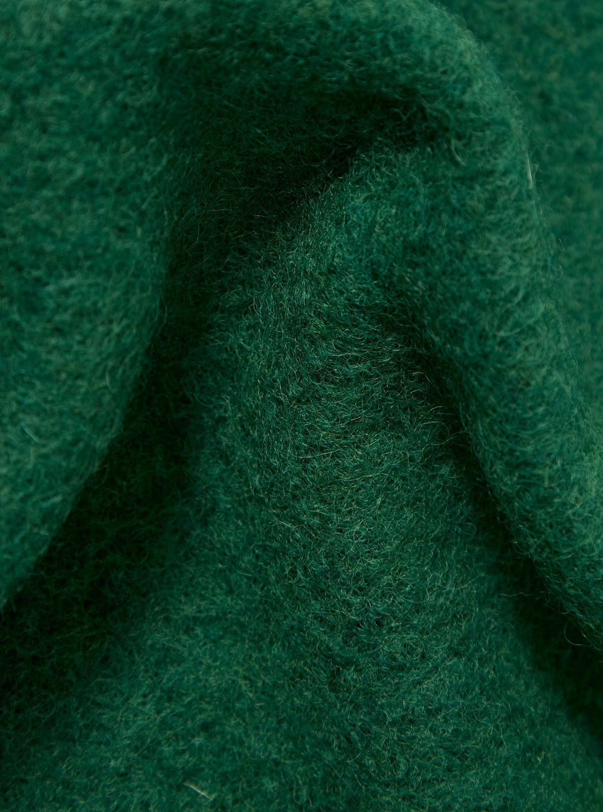 Close-up of the textured green wool fleece of a Green Wool Fleece Cardigan. The fabric is folded, showing the depth and texture of the material.