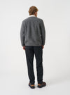 Angled view of a model wearing the Grey Marl Wool Fleece Cardigan in a studio setting. The shot shows the fit from the side, highlighting the textured grey marl fleece fabric, ribbed cuffs, and side pocket.