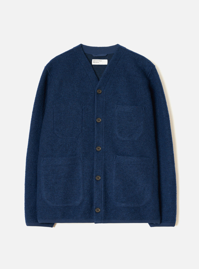 The Indigo Wool Fleece Cardigan is laid flat on a light grey studio backdrop. Features a V-neckline, five dark horn buttons down the front placket, four front patch pockets, a straight hem, and textured boiled wool fleece fabric.