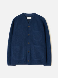 Indigo wool fleece cardigan laid flat on a light grey studio backdrop. V-neckline with a woven Universal Works label at the back neck. Five dark horn buttons down the front placket. Four patch pockets, two chest and two hip. Textured boiled wool fleece fabric. Straight hem and full-length sleeves.