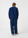 Angled view of a model wearing the Indigo Wool Fleece Cardigan in a plain studio setup. The image demonstrates the relaxed fit, cuff ribbing, and rich indigo blue wool fleece texture from the side.