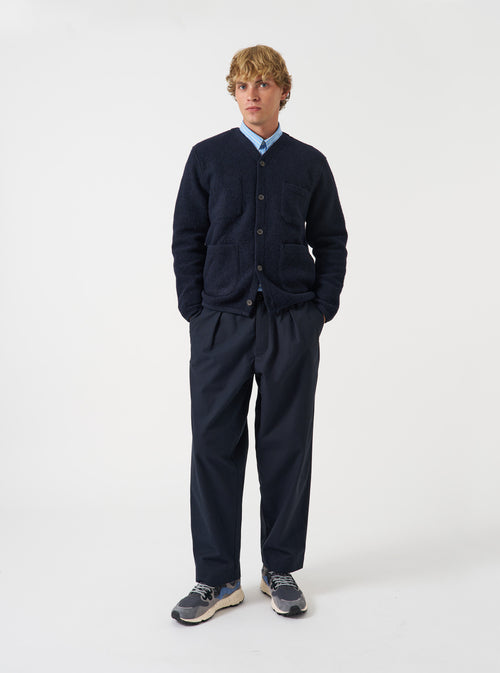Front view of a model wearing the Navy Wool Fleece Cardigan in a studio setting with a light backdrop. The model stands facing forward, showcasing the classic dark navy shade, button front, and patch pockets.