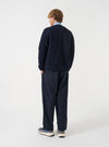Angled view of a model wearing the Navy Wool Fleece Cardigan in a plain studio setting. The shot demonstrates how the cardigan fits from the side, highlighting the dark navy wool fleece and ribbed hem.