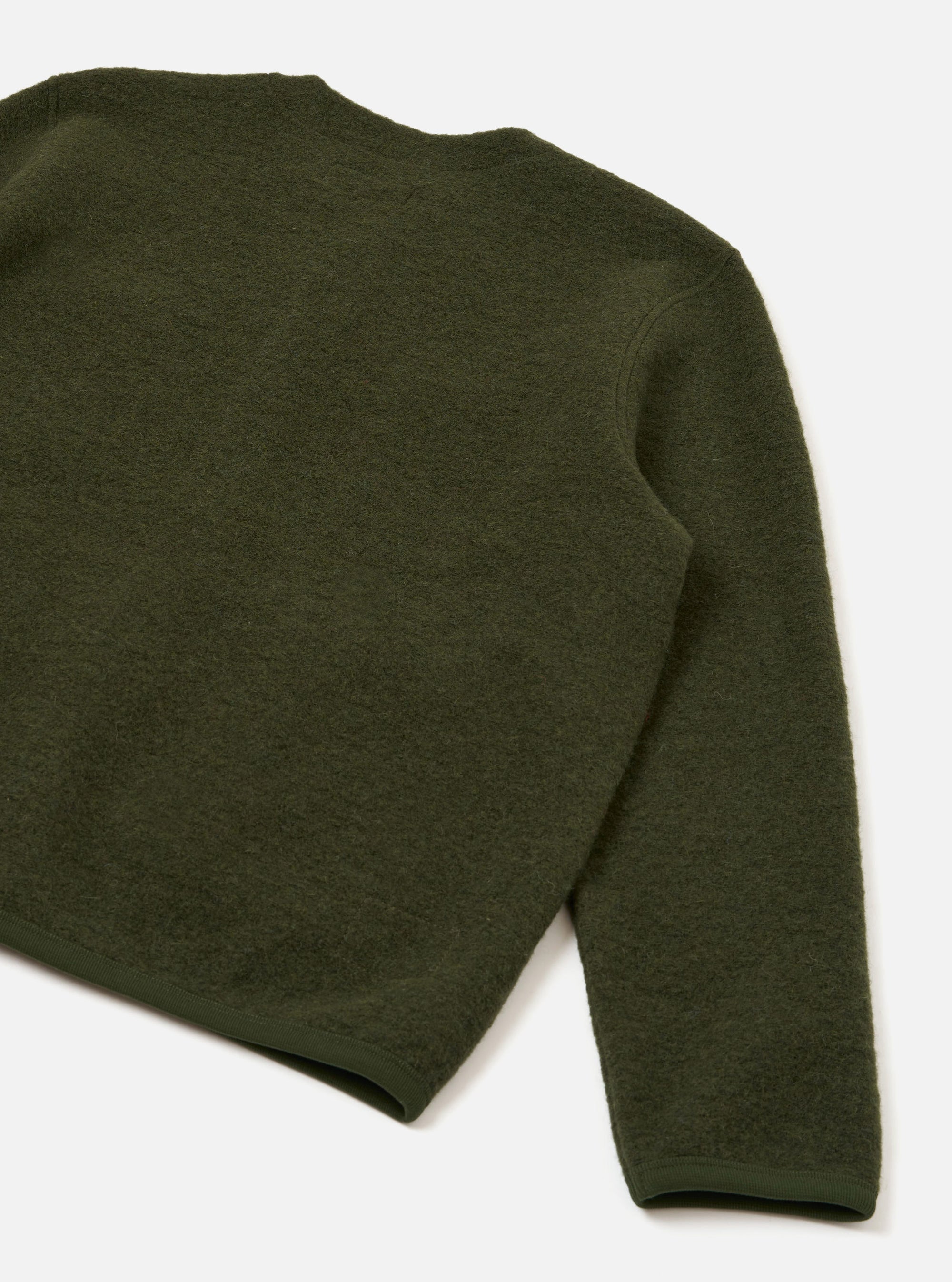 Close-up rear detail of an olive wool fleece cardigan, flat lay on a white studio surface. The shot shows the back panel and one full sleeve, highlighting the dense, textured fleece fabric. A ribbed hem and ribbed cuff are visible at the edges.