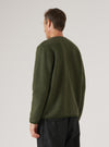 Back view of a male model wearing an olive wool fleece cardigan on a light grey studio backdrop. The textured, brushed fleece fabric is shown clearly across the back and full-length sleeves. A crew neckline and ribbed hem are visible. The cardigan is worn untucked over dark charcoal trousers. Shot cropped from mid-thigh up.