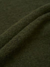 Close-up of olive wool fleece fabric, showing soft, lightly brushed texture with fine surface fibres and natural drape. The deep khaki green cloth is folded to reveal its thickness and fluffy handle. No garment details or construction are visible in this fabric detail shot.