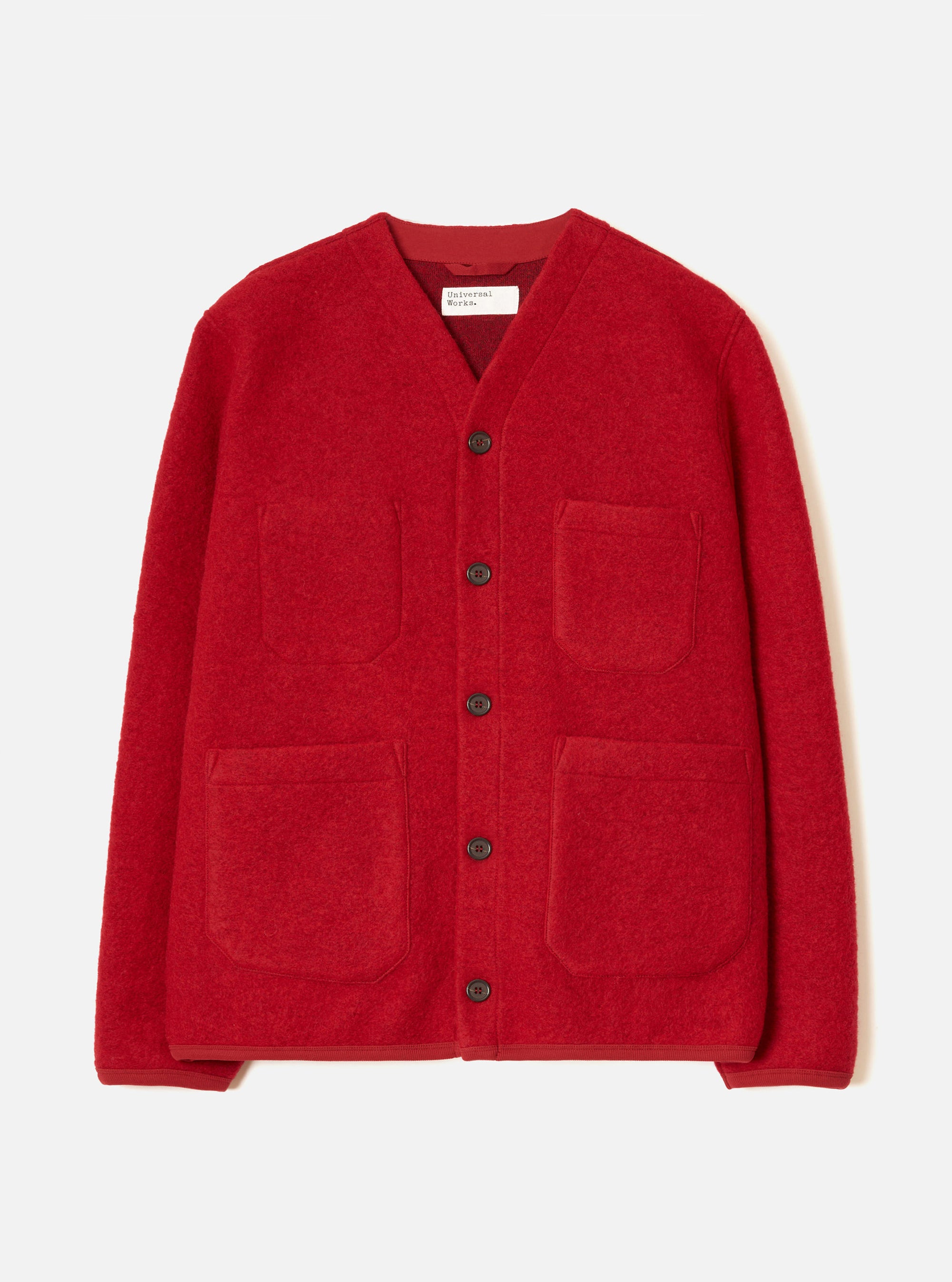 Scarlet wool fleece cardigan laid flat on a white studio backdrop. Collarless V-neckline with a Universal Works label visible at the neck. Five dark buttons down the centre front. Two chest patch pockets and two larger lower patch pockets in matching fleece. Plain cuffs and a straight hem. Textured boiled wool fleece fabric throughout.