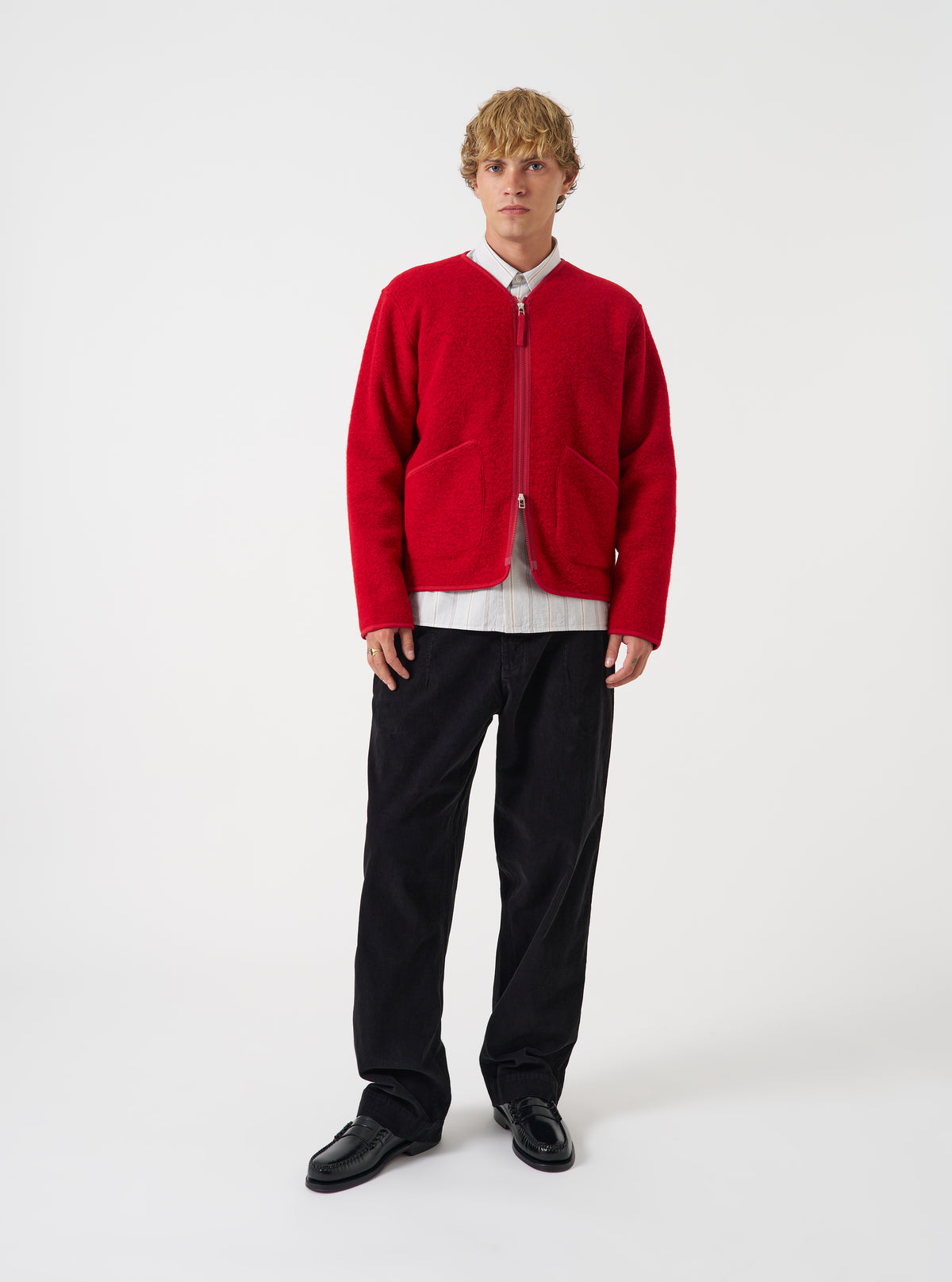 Front view of a model wearing the Scarlet Wool Fleece Zip Liner Jacket in a studio setting with a light backdrop. The model stands facing forward, showing the red fleece texture, full front zipper, and collar.