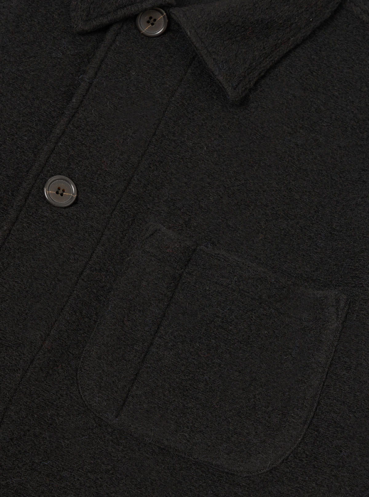Detailed close-up shot of the Black Wool Fleece Field Jacket against a plain white background, highlighting the front chest pocket details, button fastenings, and soft wool fleece fabric texture.