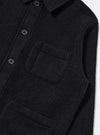 Close-up of the Black Wool Fleece Field Jacket. The jacket is black wool with button closure and chest pockets. Shot against a white backdrop.