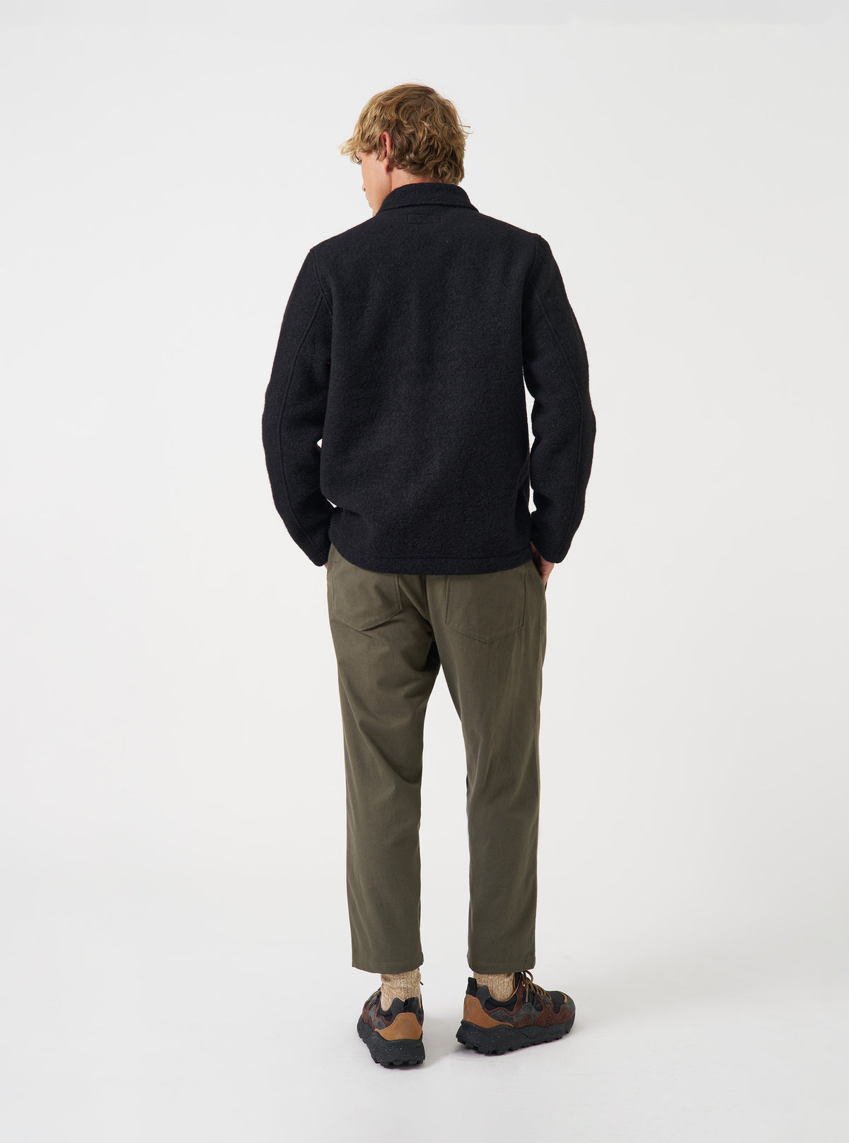 Angled rear view of a model wearing the Black Wool Fleece Field Jacket in a studio setting. Highlights the fit across the shoulders and back using a clean, plain studio background.