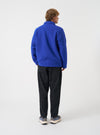 Side angled view of a model wearing the Blue Wool Fleece Field Jacket in a plain studio setting, illustrating the sleeve fit, side profile, and rich dark blue wool fleece fabric.
