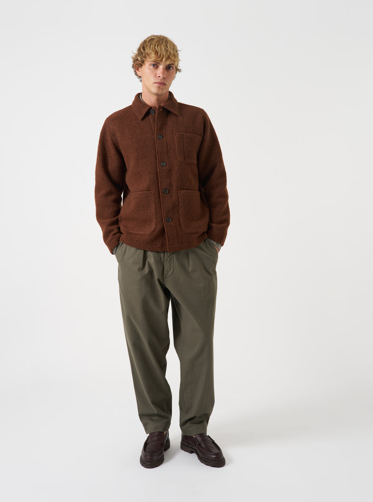 Front view of a model wearing the Cacao Wool Fleece Field Jacket in a studio setting with a light backdrop. The model stands facing forward, displaying the jacket's brown color and fit.