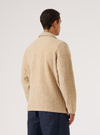 A man stands in front of a white background, wearing a Fawn Wool Fleece Field Jacket and dark blue pants. The jacket is made of wool fleece.
