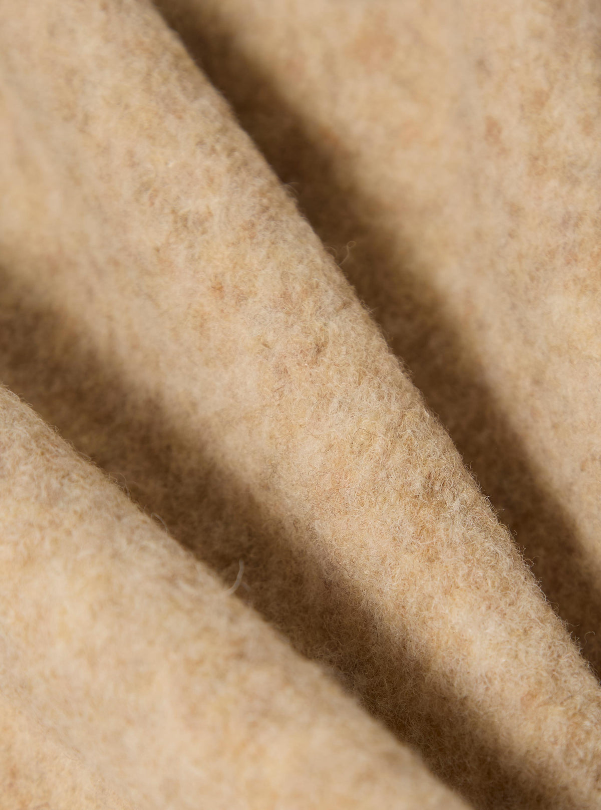 Close-up of the Fawn Wool Fleece Field Jacket. The soft, fawn-colored wool is folded, showing its texture. The image is tightly cropped, highlighting the material.