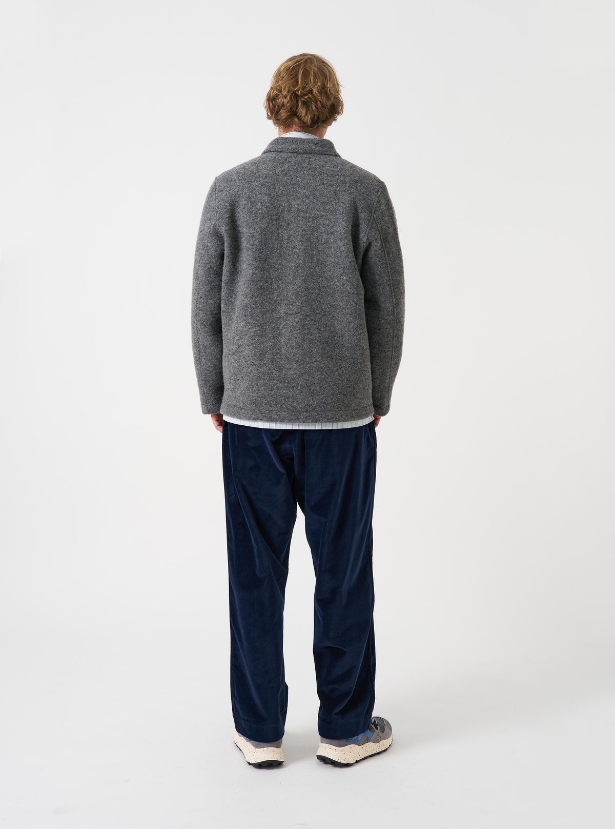 Angled side view of a model wearing the Grey Marl Wool Fleece Field Jacket in a studio backdrop. The shot demonstrates the garment fit, showing long sleeves and soft grey marl fleece texture in detail.