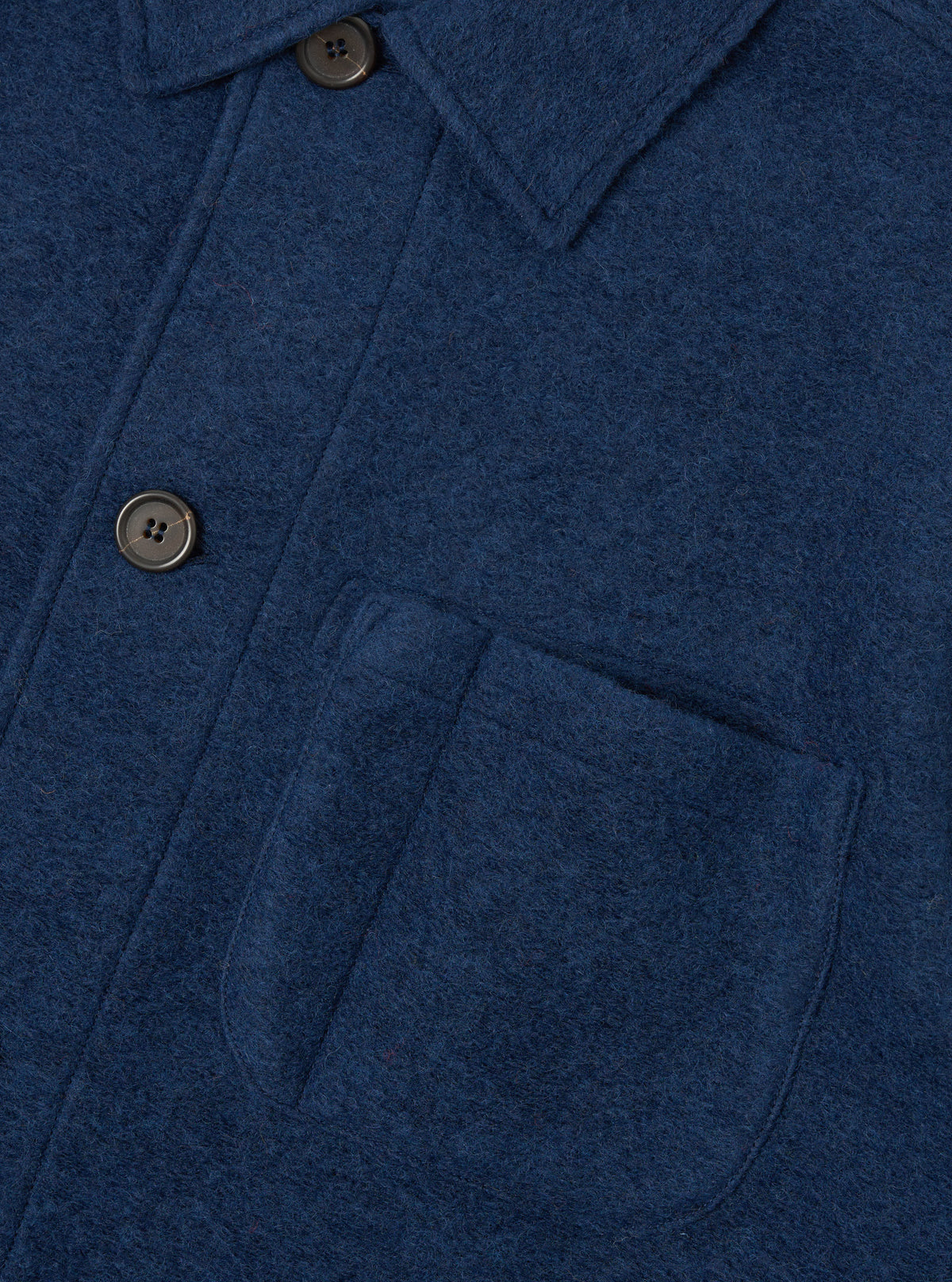 Detailed close-up shot of the Indigo Wool Fleece Field Jacket on a white backdrop. Focuses on the textured wool fleece material, fine stitching, button placket, and flap pocket construction.
