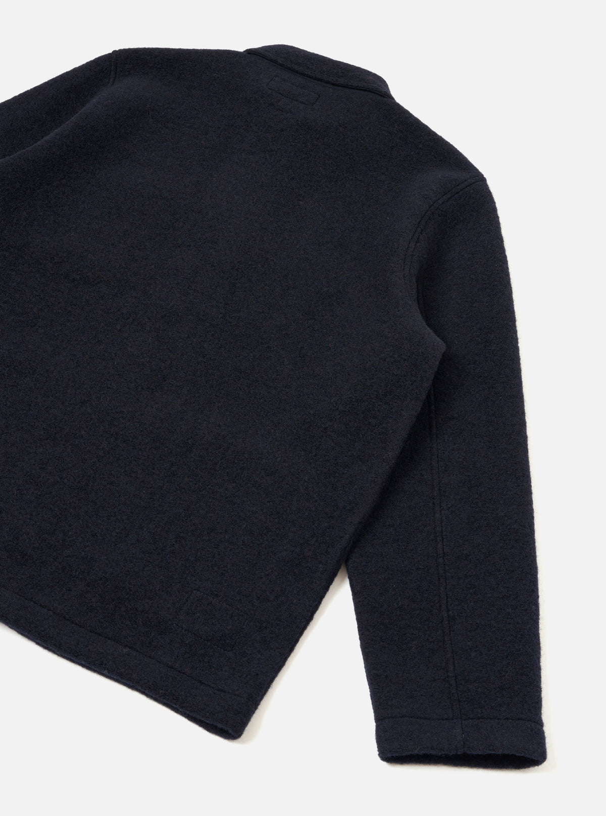 Rear view of the Navy Wool Fleece Field Jacket set against a clean white backdrop. Shows the simple back cut, straight hem, long sleeves, and soft deep navy wool fleece fabric construction.