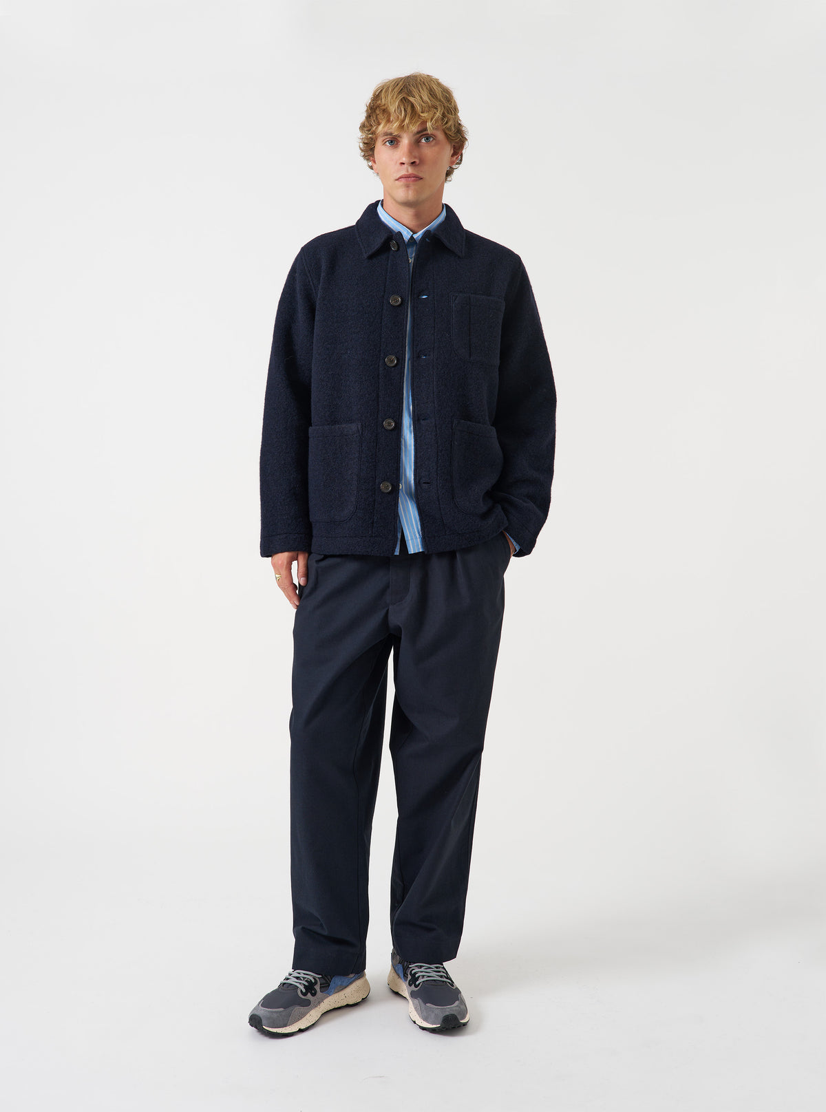 Front view of a model wearing the Navy Wool Fleece Field Jacket standing in a clean studio setting. The model faces forward, illustrating the dark navy garment fit, sleeve length, and button front.