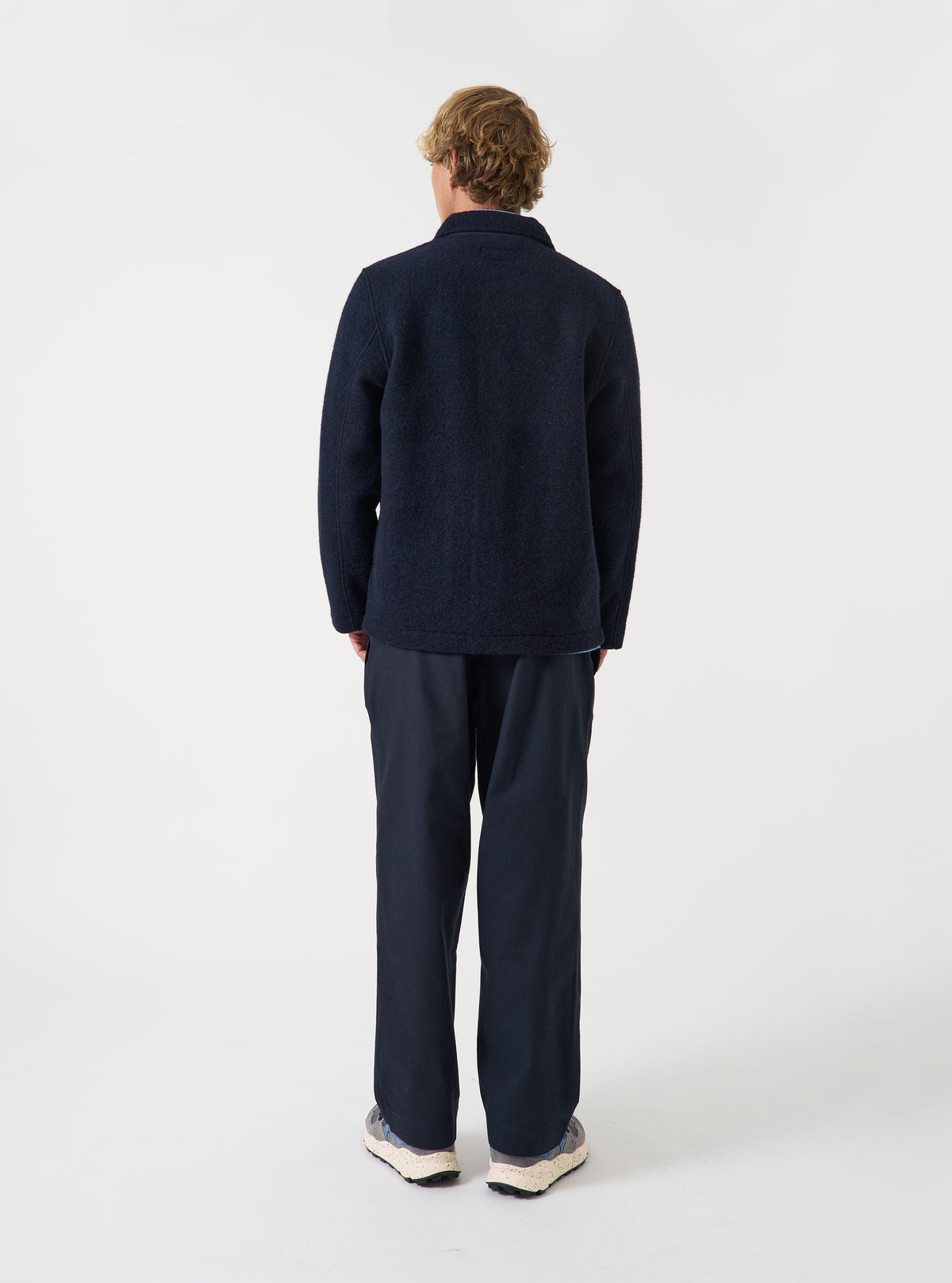 Angled view of a model wearing the Navy Wool Fleece Field Jacket in a minimalist studio environment. Highlights the casual fit, side profile, and rich navy wool fleece texture of the jacket.