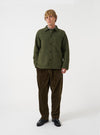Front view of a model wearing the Olive Wool Fleece Field Jacket in a plain studio setting. The model stands facing forward, showing the olive green jacket fit, collar, button front, and utility pocket details.