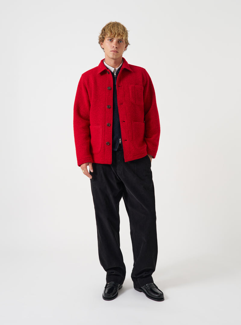 Front view of a model wearing the Scarlet Wool Fleece Field Jacket in a light studio setting. The model stands facing forward, showcasing the bright red fleece jacket paired with trousers and layered over a shirt.