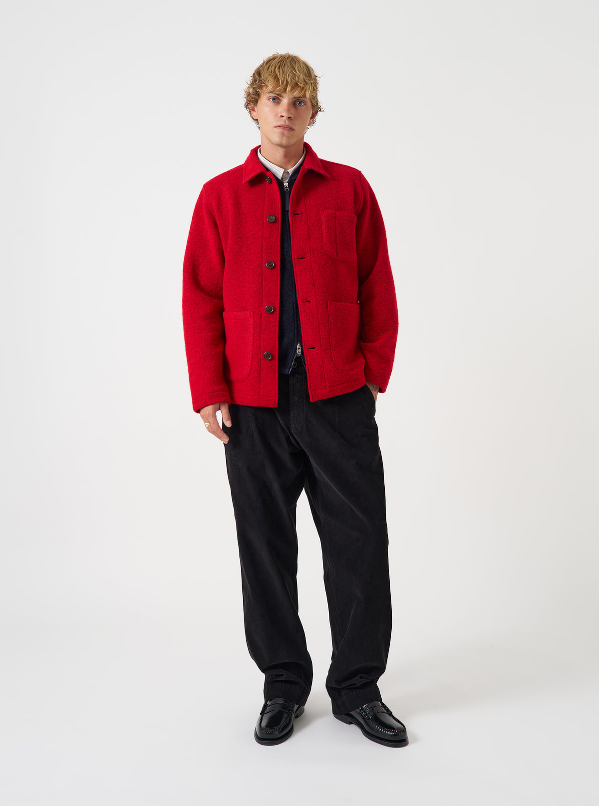 Front view of a model wearing the Scarlet Wool Fleece Field Jacket in a light studio setting. The model stands facing forward, showcasing the bright red fleece jacket paired with trousers and layered over a shirt.