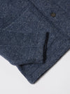 Close-up of the slate blue Wool Fleece Field Jacket on a white surface. The wool texture and button are visible.