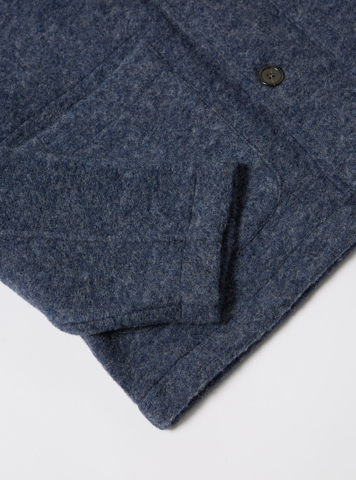 Close-up of the slate blue Wool Fleece Field Jacket on a white surface. The wool texture and button are visible.