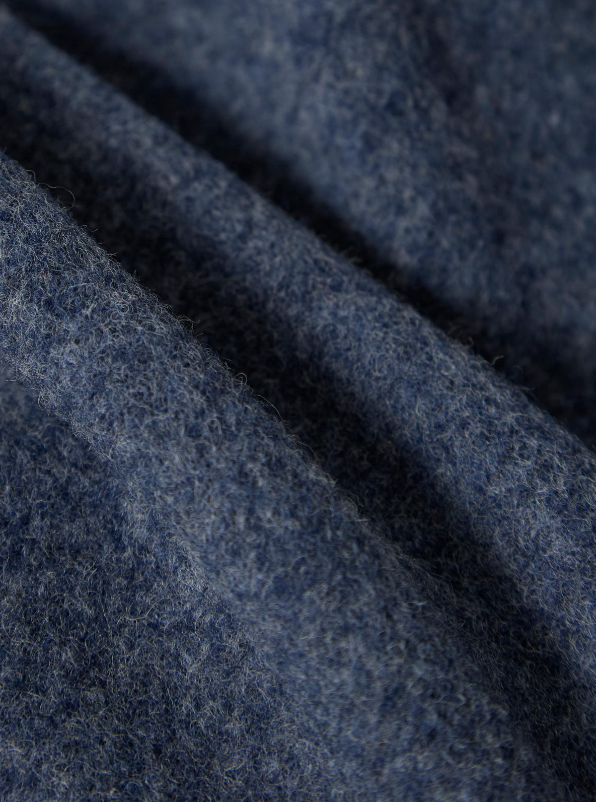 Close-up of the Slate Blue Wool Fleece Field Jacket. The soft, textured wool is draped and folded, showcasing its color and material. 